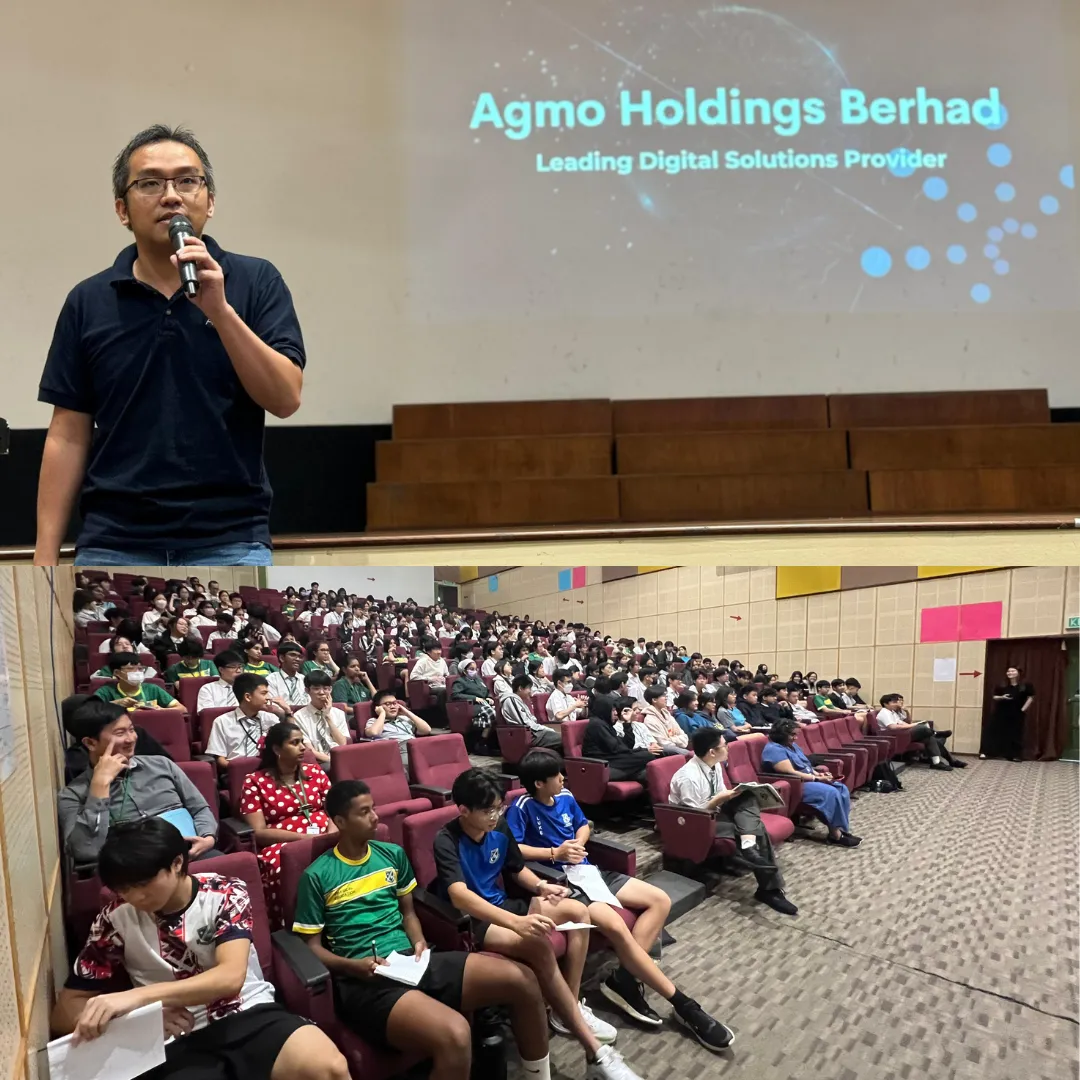 Speaker addressing a large audience under an Agmo Holdings Berhad presentation screen