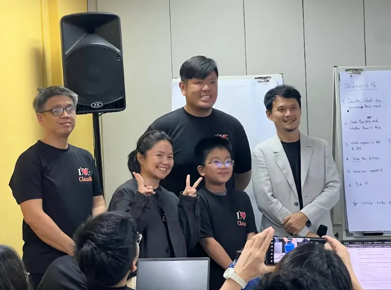 A family of three smiling and making peace signs at the front of the room with two trainers after the Claude class