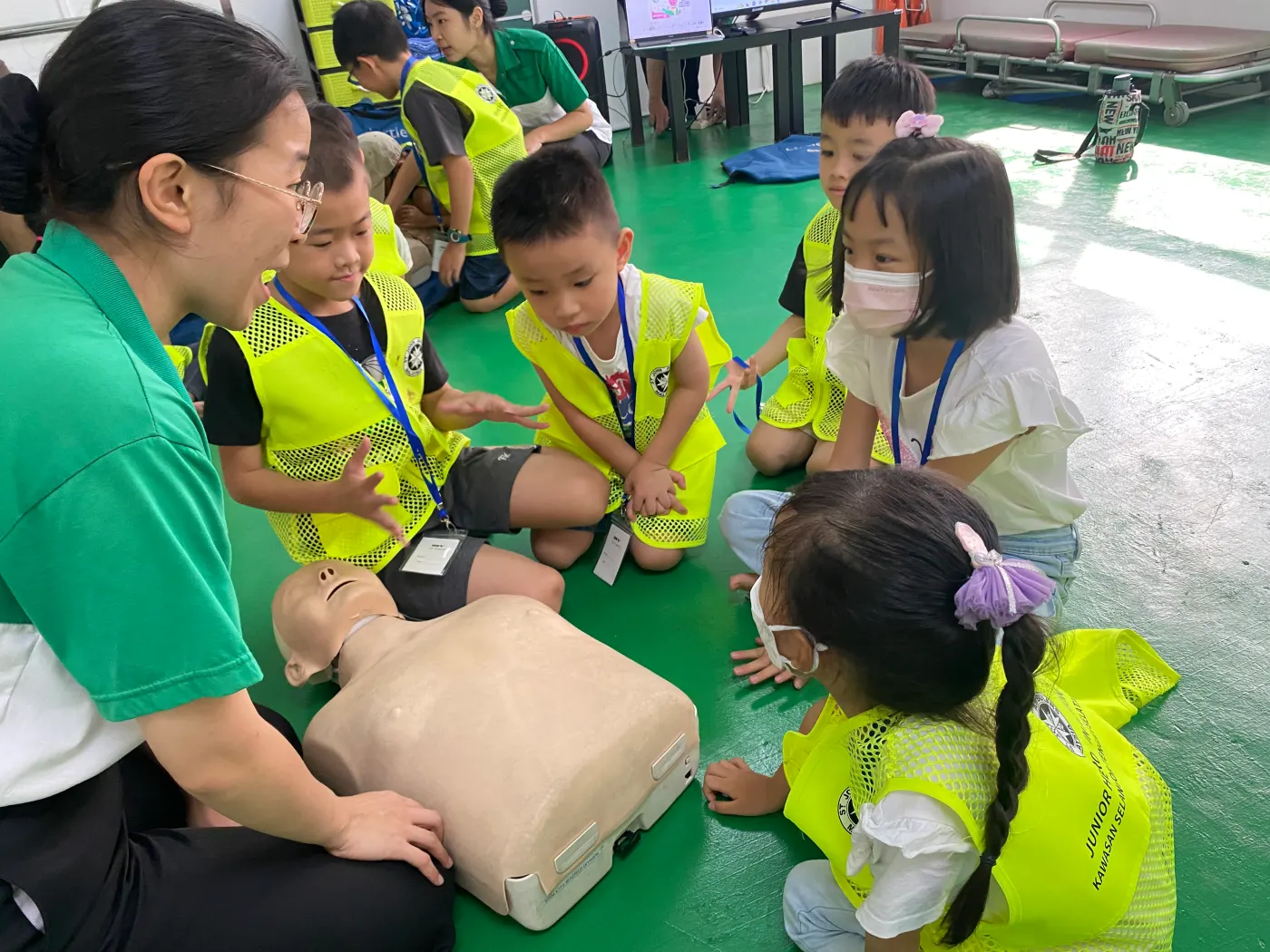 Children practising CPR on a training manikin with a St John Ambulance instructor
