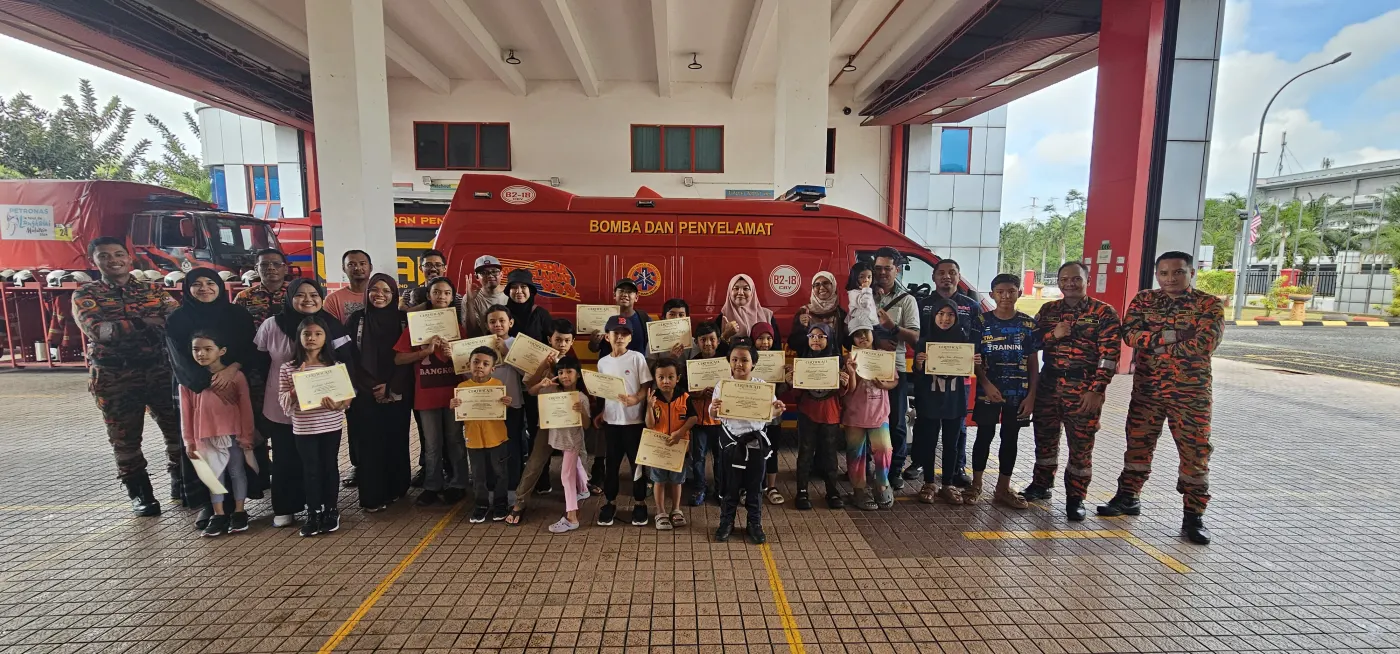 Children and Bomba officers in front of a fire truck at the Junior Firefighters session