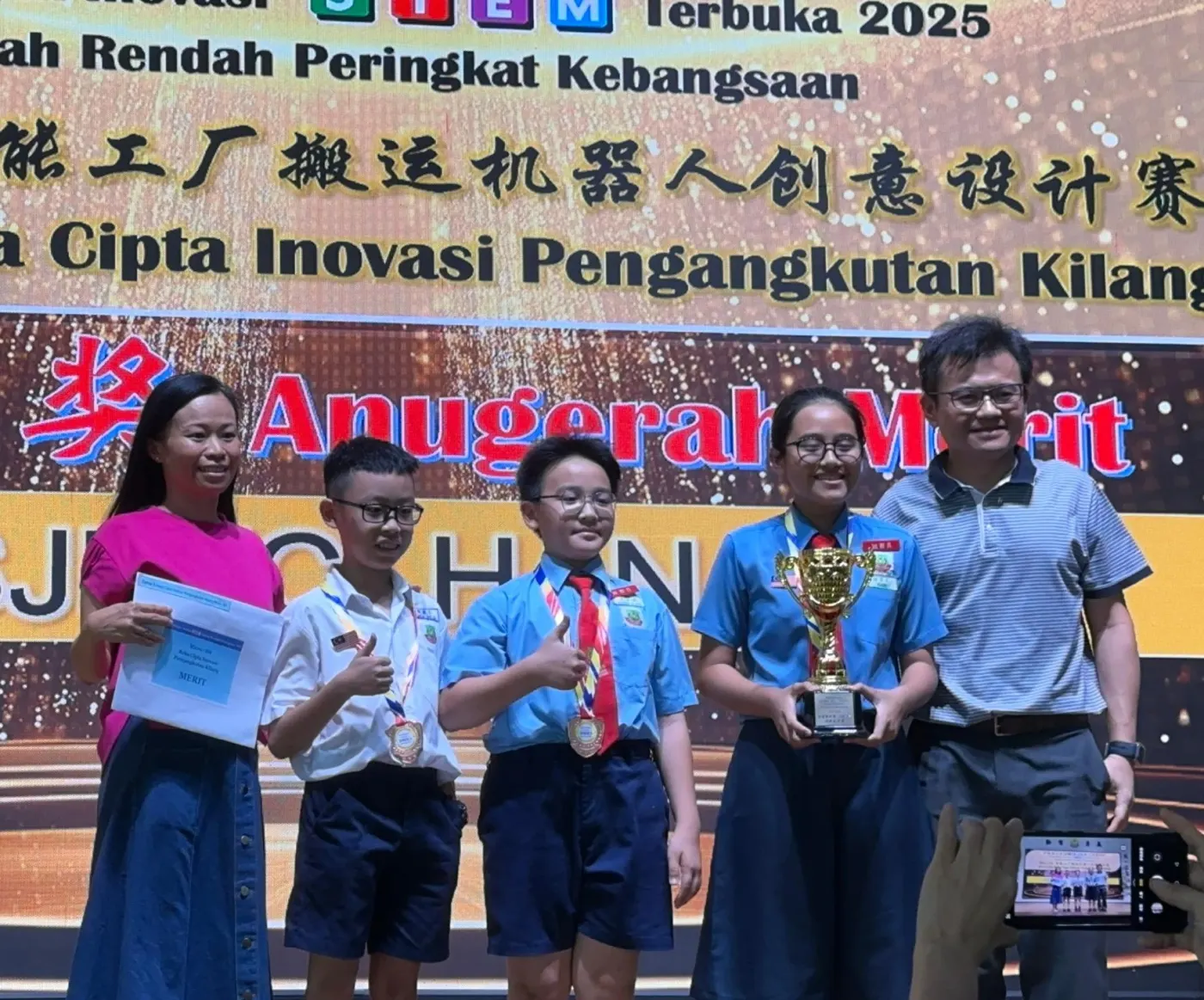 Agmo Junior team on stage receiving their merit award at the Reka Cipta Inovasi Pengangkutan Kilang competition