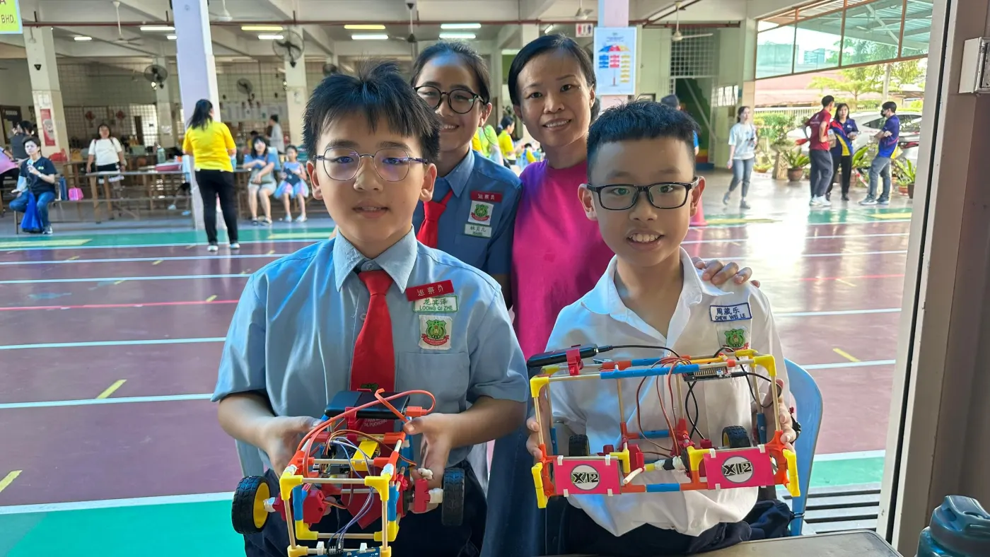Two Agmo Junior students holding their robot and certificate after the micro:bit competition