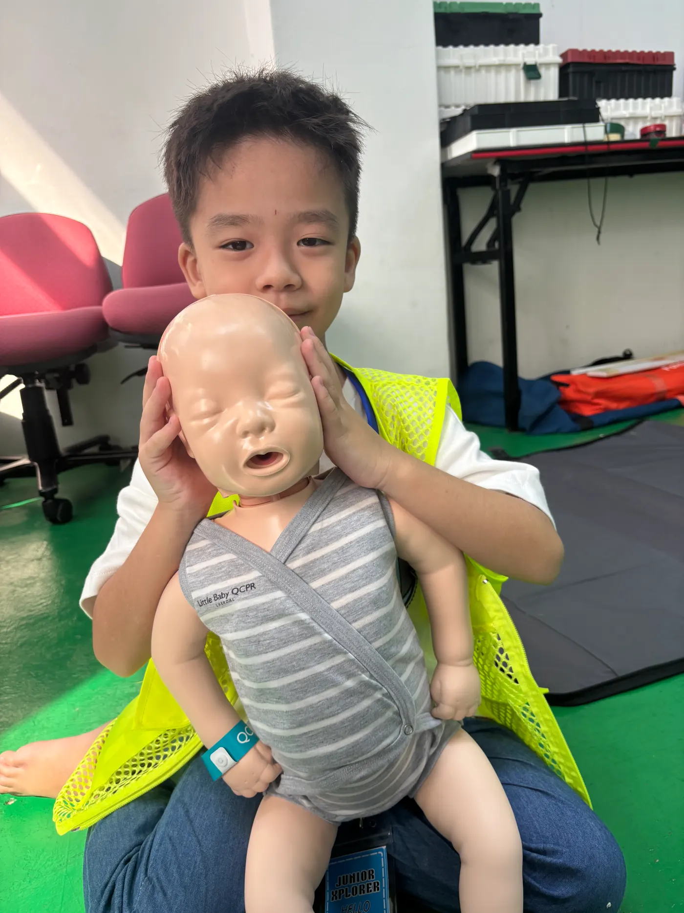 A kid holding a dummy baby that they were taught how to perform CPR on.