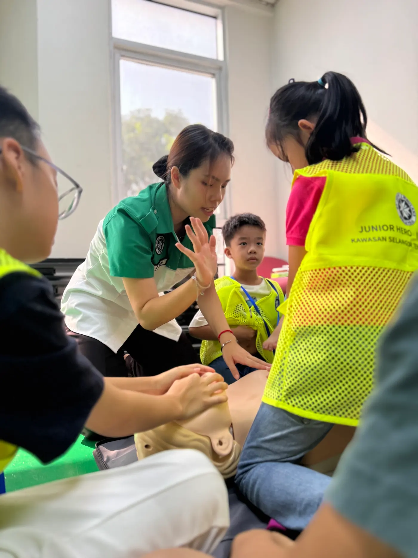 A St Johns Malaysia intructor teaching kids how to perform CPR on a dummy.
