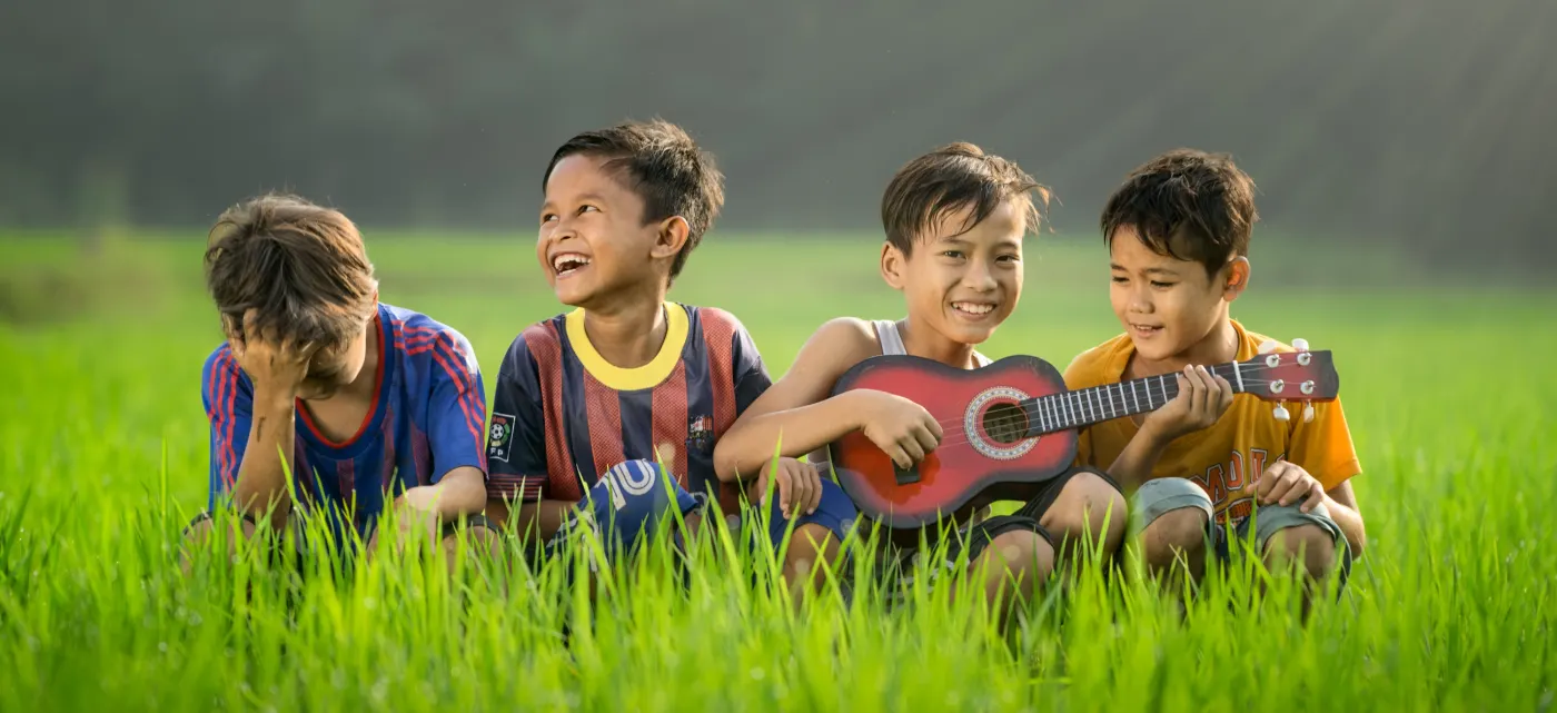 Kids being kids playing the guitar in a field