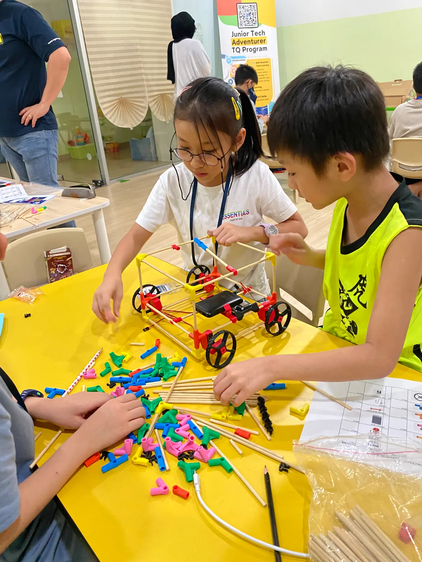 Two students building a colourful vehicle from connectors