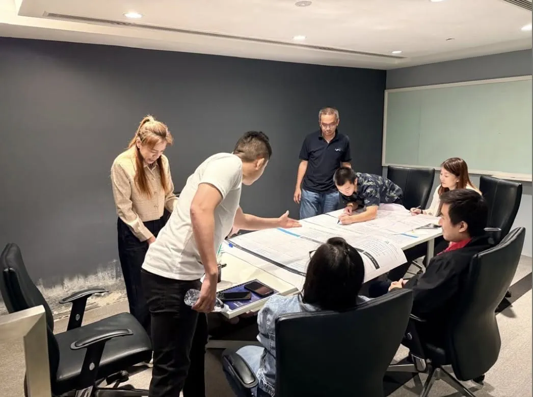 Participants and a trainer gathered around a table working through a printed planning sheet during a team exercise